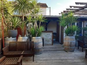 eine Terrasse mit Holzbänken und Topfpflanzen in Fässern in der Unterkunft Maison Escale Dax N78 in Dax
