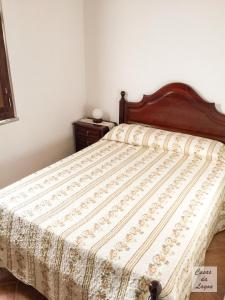 a bed in a bedroom with a wooden headboard at Casas Da Lagoa - T2 Norte in Aldeia de Brescos