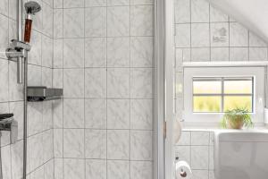 a white bathroom with a shower and a window at Haus Deichperle Tini Anton in Dornum +37 photos