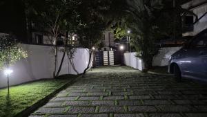 a brick sidewalk with a gate at night at Thistle Cosy Villa in Kozhikode +28 photos