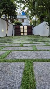 a stone walkway with grass in front of a house at Thistle Cosy Villa in Kozhikode