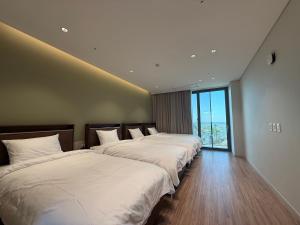 three beds in a room with a large window at Seohaemaroo Youthhostel in Hwaseong +15 photos