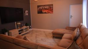 a living room with a couch and a flat screen tv at Comfy stay in East London