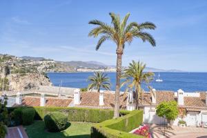 a view of a house with palm trees and the ocean at Apartamento Vistamar Marina in Almuñécar