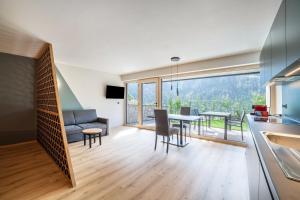 a kitchen and living room with a table and a couch at Aktiv Lodge Meran - Garden Two in Saltusio