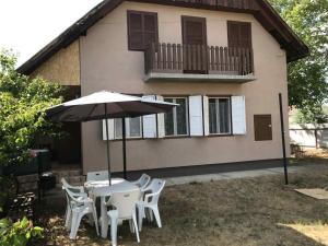 a table and chairs with an umbrella in front of a house at Tomi Vendégház in Kóczántanya