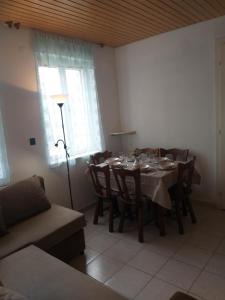 a dining room with a table and chairs and a lamp at Tomi Vendégház in Kóczántanya +6 photos