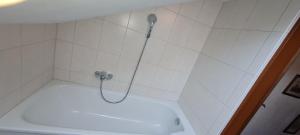 prysznic z wężem w wyłożonej białymi kafelkami łazience w obiekcie Haus Bergblick w mieście Mittenwald