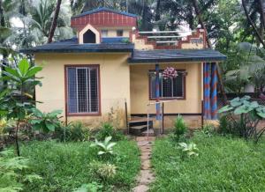 a small house in the middle of a garden at Tuka Maka Homestay in Malvan