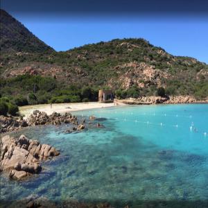 a beach with rocks and blue water and a mountain at Casa Turchese in Olbia