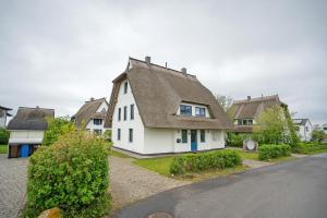 une maison blanche avec un toit gris et une rue dans l'établissement Ferienhaus Seestern, à Dranske