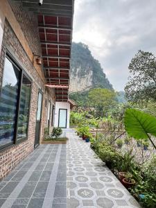 a brick building with a walkway with a mountain in the background at Tam Coc Mountain Light Homestay in Ninh Binh