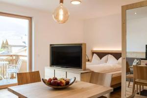 a living room with a television and a bowl of fruit on a table at Natur Suite Edelweisshof App Ferdi in Chiusa