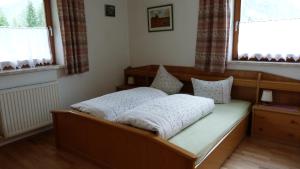 Bett in einem Zimmer mit Fenster in der Unterkunft Landhaus Genoveva in Leutasch