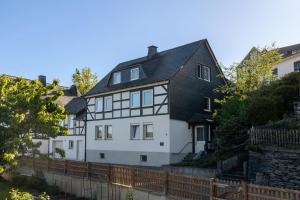a white and black house with a fence at Ferienwohnung am Hügel in Schmallenberg