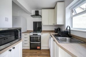 eine Küche mit weißen Schränken und einer Spüle in der Unterkunft Beach Meets City - Two Bed Stay Near to Liverpool in Wallasey