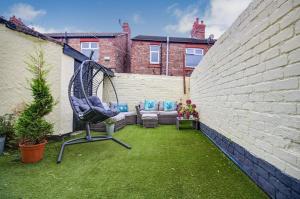 eine Terrasse mit Stuhl und Sofa im Garten in der Unterkunft Beach Meets City - Two Bed Stay Near to Liverpool in Wallasey