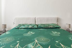 a bed with a green comforter and two pillows at Matera Castle Suite in Matera