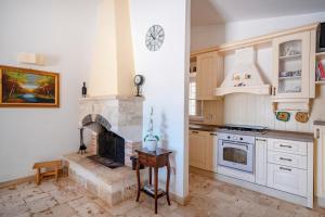 a kitchen with a fireplace in the middle of it at Villa Trullo Ulivo with pool in Carovigno