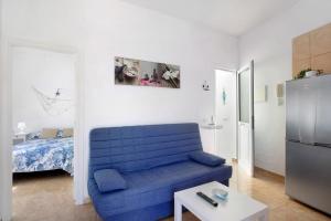 ein Wohnzimmer mit einem blauen Sofa und einem Kühlschrank in der Unterkunft Atico Las Arenas in Arico