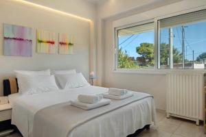 een slaapkamer met een wit bed met handdoeken erop bij Beach Family Villa in Artemida in Artemida