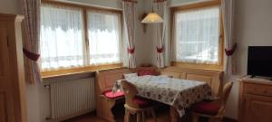 a dining room with a table and chairs and windows at Apartments Goller in Ortisei
