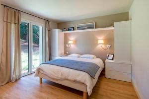 a bedroom with a bed and a large window at Villa proche du lac d'Hossegor in Soorts-Hossegor