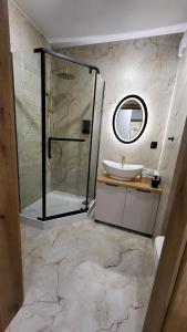a bathroom with a shower and a sink and a mirror at Apartament Anna przy Starówce in Zamość