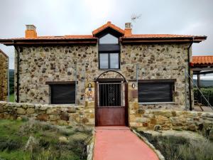 une maison en pierre avec une porte en bois et une allée rouge dans l'établissement La Casona del Silencio, à Aldehuela de Periañez