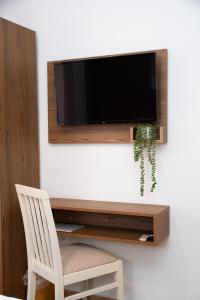 a flat screen tv hanging on a wall with a white chair at Akti Luxury Rooms & Apartments in Olympiaki Akti