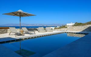 a swimming pool with two chairs and an umbrella at ANOTERRA VILLAS -Anassa in Ambelas
