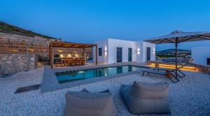 a villa with a swimming pool at night at ANOTERRA VILLAS -Anassa in Ambelas