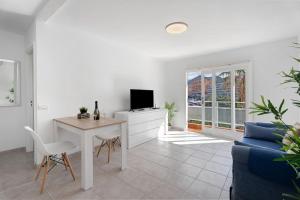 アロナにあるBonito Apartamento Cristian Playaの白いリビングルーム(テーブル、テレビ付)