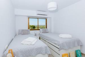 two beds in a white room with a window at Tamarinda in Jávea +15 photos