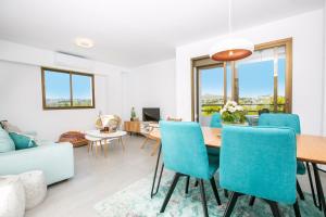 a living room with a dining room table and blue chairs at Tamarinda in Jávea