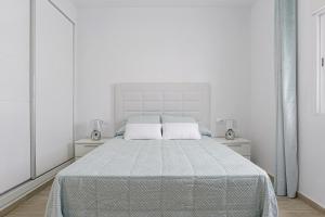 Un dormitorio blanco con una cama grande con dos almohadas. en Casa Caramelo, en La Muela 15 fotos más