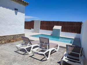 a pair of chairs sitting next to a swimming pool at Finca La Vigia 2 in Conil de la Frontera