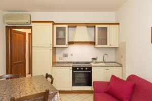 een keuken met witte kasten en een rode bank bij Il Girasole - Malva in Venturina Terme