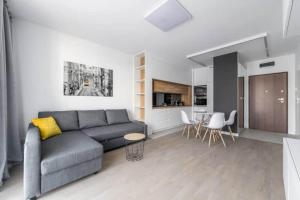 una sala de estar con un sofá, una mesa y sillas en Exclusive Apartments on Kasprzaka Street - Warsaw Wola, en Varsovia