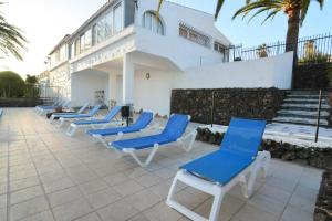 a row of blue and white chairs on a patio at Bungalow con piscina comunitaria in Chayofa
