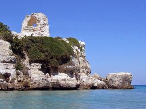 eine felsige Insel mit einem Gebäude im Wasser in der Unterkunft Bilocale centralissimo vista mare 29 in Torre dell'Orso + 12 Fotos