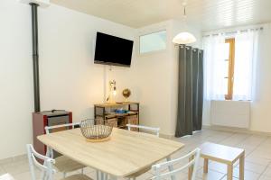 a dining room with a table and chairs and a television at Chez roger in Chanaz