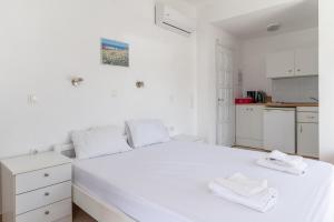 a white bedroom with a large white bed with two white towels at Sifnos studio 6 in Sifnos +14 photos