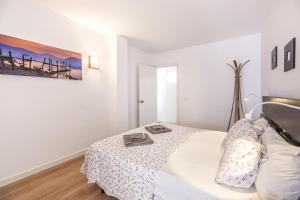 a white bedroom with a bed and a table at Aire del Mar in Port de Pollensa