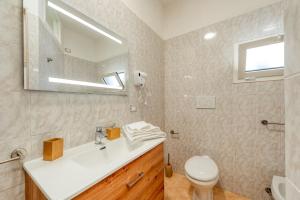 une salle de bain avec un lavabo, des toilettes et un miroir dans l'établissement San Giorgio Apartment, à Cavallino di Lecce
