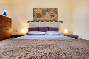 Un dormitorio con una cama grande con almohadas moradas. en La Palmera de la Oliva, en La Oliva 19 fotos más