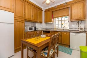een keuken met houten kasten en een houten tafel met stoelen bij 10T2 by AlgarveManta in Manta Rota