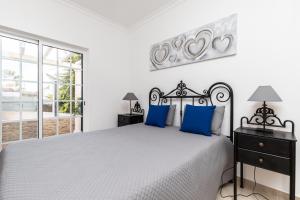 een witte slaapkamer met een groot bed met blauwe kussens bij 10T2 by AlgarveManta in Manta Rota