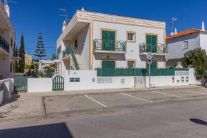 een groot wit huis met groene ramen en een hek bij 10T2 by AlgarveManta in Manta Rota