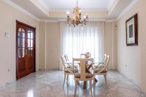 a dining room with a table and chairs and a chandelier at Villa Candelaria Sol y Piscina in Bormujos